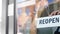 happy woman hanging reopen banner to door glass