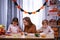 Happy woman with her daughter and son getting ready for Halloween. The family sits at the table, the mother helps the