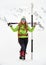 Happy woman hiker with trekking poles, backpack and snow gaiters, next to a tall trail marker in Winter, with poor visibility.