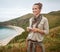 Happy woman hiker writing sms in front of ocean view landscape