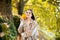 Happy woman holding autumn leafs on face in fall nature. Portrait of young woman with autumn maple leaves outdoor