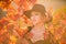 Happy woman holding autumn leafs on face in fall nature. Portrait of young woman with autumn maple leaves outdoor