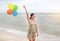 Happy woman holding balloon on beach on vacation. Holiday concept