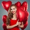 Happy woman holding balloons red heart. Surprise, valentines people and Valentine`s day concept. Red lips makeup.