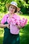 Happy woman holding basket of roses in garden.