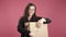 Happy woman holding box on pink background.