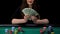 Happy woman holding dollars bunch, sitting at casino table, game winner, success