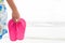 Happy woman holding pink flip flop on sandy beach for summer