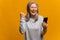 Happy woman holding smartphone and smiling making yes gesture, celebrating online lottery or giveaway victory. Indoor