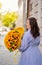 Happy woman with huge bouquet of decorative sunflowers walks along city street
