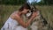 Happy woman hugging and kiss alaskan malamute dog in summer field