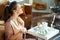 Happy woman with jar applying neck cream and looking in mirror