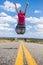 Happy woman jumping over american road