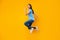 Happy woman jumping over yellow studio wall