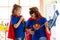 Happy woman and kid prepare for room cleaning. Mother and her child girl playing together. Family in Superhero costumes.