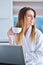 Happy woman in the kitchen reading he news on her laptop