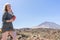 Happy woman laughing, reading a message from social media in her smart phone in a desert spot in the famous volcano El Teide, in
