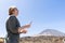 Happy woman laughing, reading a message from social media in her smart phone in a desert spot in the famous volcano El Teide, in