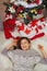 Happy woman laying near Christmas tree. Upper view