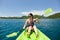 Happy woman with lifejacket kayaking in tropical island ocean on vacation.