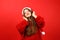 Happy woman listening to music with headphones wearing santa hat on red background. Enjoy holiday songs