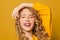 Happy woman with long curly hair smiling on bright yellow background