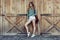 Happy woman with long legs look to the side near barn on the farm wearing casual outfit with shorts, backpack and sneakers.