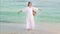 Happy woman in the long white dress spinning and dancing at the ocean sea beach