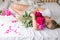 Happy woman lying on the bed wearing pajamas, enjoying tulip flowers bouquet of peony