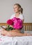 Happy woman lying on the bed wearing pajamas, enjoying tulip flowers bouquet of peony