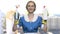 Happy woman maid holding two bottles of detergent.