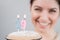 The happy woman makes a wish and blows out the candles on the 29th birthday cake. Smiling girl celebrating birthday.