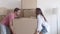 Happy woman and man coming into room, carrying, huge box