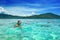 Happy woman with a mask floating in the azure tropical sea