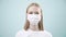 Happy woman in medical mask look and show thumb up, cool, to the camera on light background. Health protection Corona Virus