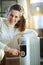 Happy woman at modern home in sunny winter day turn on radiator