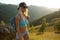 Happy woman mountain hiker with backpack and smile to you on mountain top