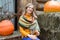 Happy woman with a mug of tea in her hand sits against the background of orange pumpkins in the courtyard of a rural house.
