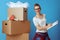 Happy woman near cardboard box marking moving checklist on blue