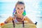 Happy woman on ocean shore showing beach straw bag