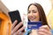 Happy woman pays online with credit card in the street