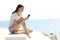 Happy woman with perfect legs using phone on the beach