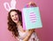 Happy woman on pink background showing Easter shopping bag
