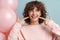 Happy woman pointing finger at her smile while posing with pink balloons