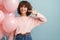 Happy woman pointing finger at smile while posing with pink balloons