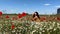 happy woman in poppy with chamomile flowers field