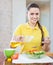 Happy woman pouring oil from bottle into salad