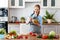 Happy woman preparing vegetable salad in kitchen