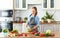 Happy woman preparing vegetable salad in kitchen