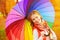 Happy woman with rainbow multicolored umbrella under rain in par